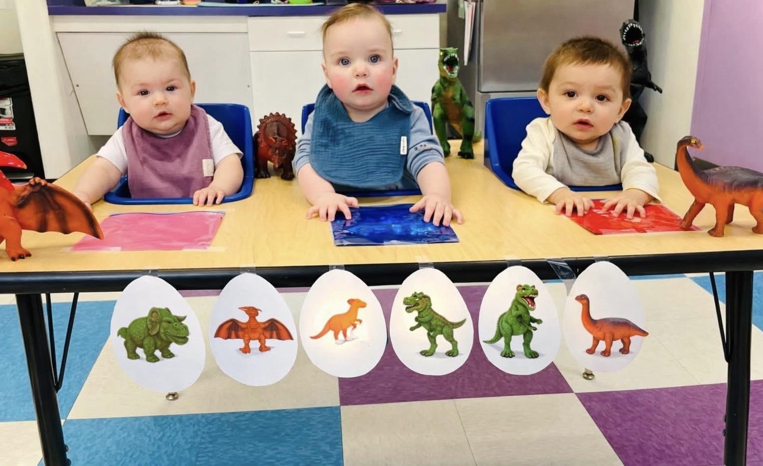 Three babies with dinosaur toys